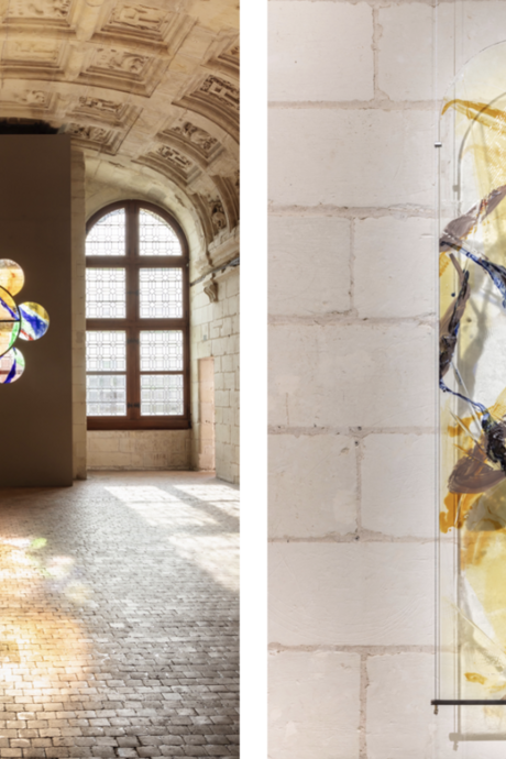Partie gauche : Nous voyons une grande salle ancienne avec des murs et un plafond voûté en pierre sculptée. Deux grandes fenêtres à arc en plein cintre laissent entrer la lumière naturelle. Entre ces fenêtres, un mur moderne gris est installé, percé de huit cercles formant une fleur stylisée. Ces cercles sont constitués de vitraux colorés aux teintes chaudes (orange, jaune) et quelques touches de bleu et de violet, créant des motifs abstraits. La lumière traverse les vitraux et projette leurs couleurs vives