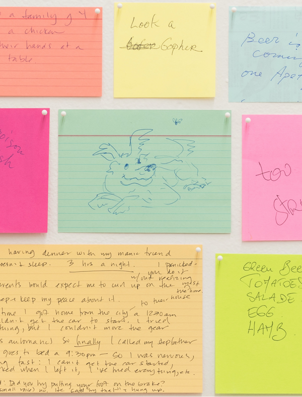 L’image montre un mur avec plusieurs notes de différentes couleurs, épinglées en grille. Chaque note contient des messages manuscrits variés, souvent liés à la nourriture, des souvenirs ou des réflexions personnelles.