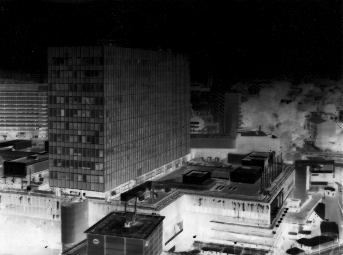 Image d'une photographie en noir et blanc représentant une ville. Un voile en dégradé a été apposé sur l'image, créant ainsi une atmosphère irréelle. 