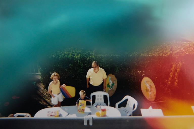 Famille prenant son petit déjeuner au soleil dans les années 90. Photographie en plongée.