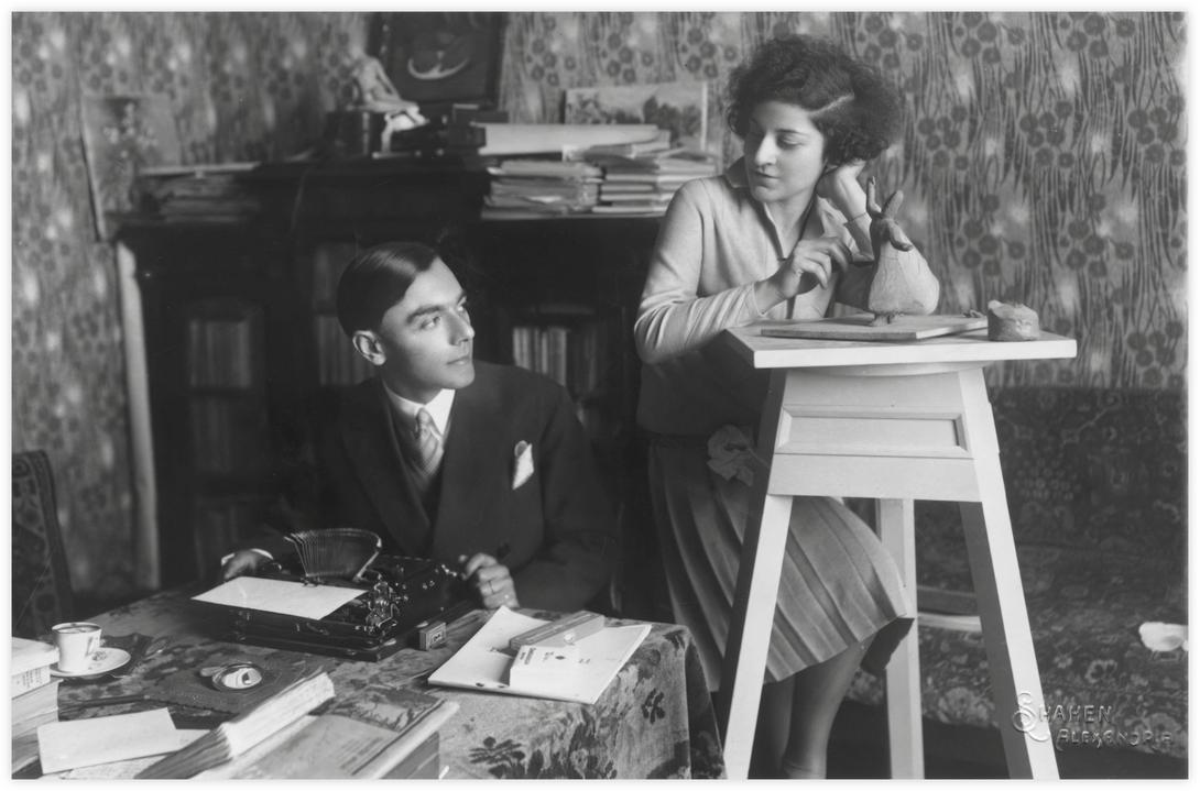 26 Daria et Imre ensemble Alexandrie. Photo Shahen vers 1930 Une autre prise de vue à Alexandrie dans la maison familiale de Daria. Les jeunes mariés se regardent. On voit une bibliothèque replie de livres à l'arrière. Daria a posé l’ébauche de sculpture du « derviche tourneur » sur une stèle.