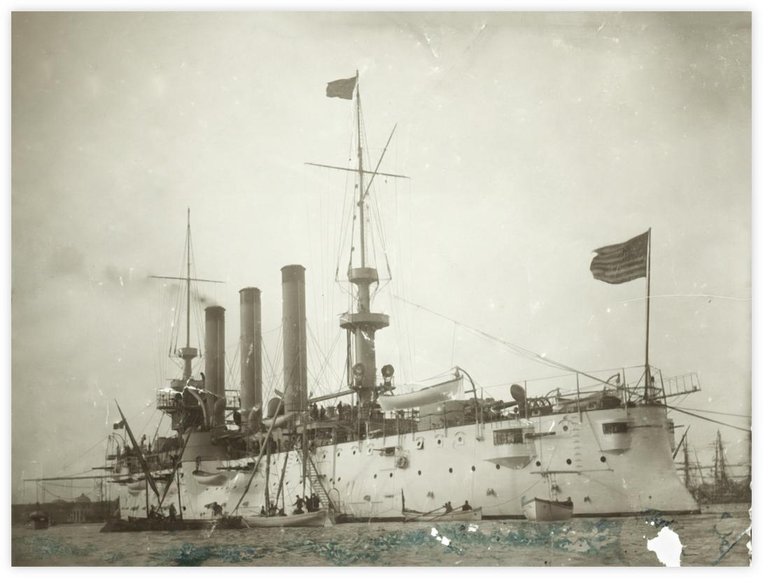 Cuirassé (1901) - Cette image semble être celle du cuirassé USS New York (ACR-2) qui est transféré à la flotte d’Asie en 1901 en passant par Gibraltar, Port Saïd et Singapour pour rejoindre les Philippines, puis Yokohama au Japon. Cette photo a été probablement prise au cours d'une escale à Alexandrie et le photographe a tenu à envoyer cette photo à "M. Achabahian¨, à Zagazig, aux bons soins des frères Gamsaragan (verso de la photo). Les frères Gamsaragan possédaient une manufacture de tabac à Zagazig. Cett